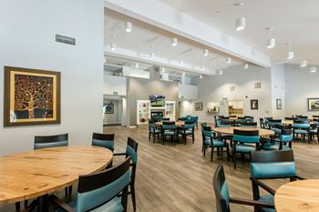 A room with tables and chairs and a painting on the wall.